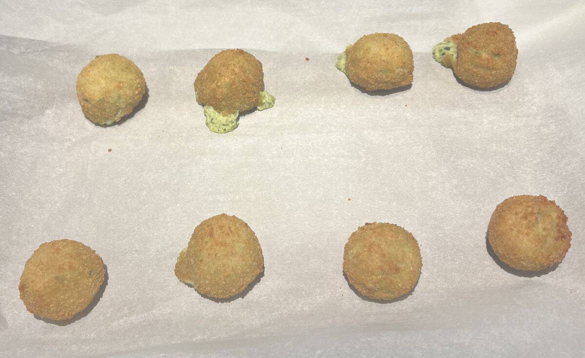 Image of the spinach & artichoke bites on a cookie tray lined with parchment paper after being baked.