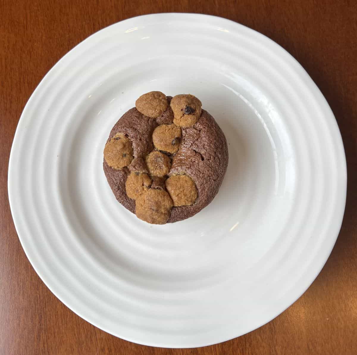 Top down image of one Brookie served on a white plate showing the brownie with cookie dough bites in the brownie.