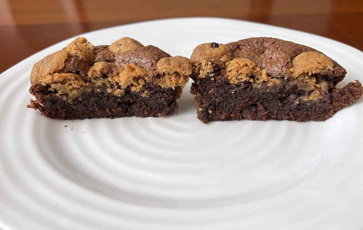 Image of a Brookie served on a white plate cut in half so you can see the center of the brownie.