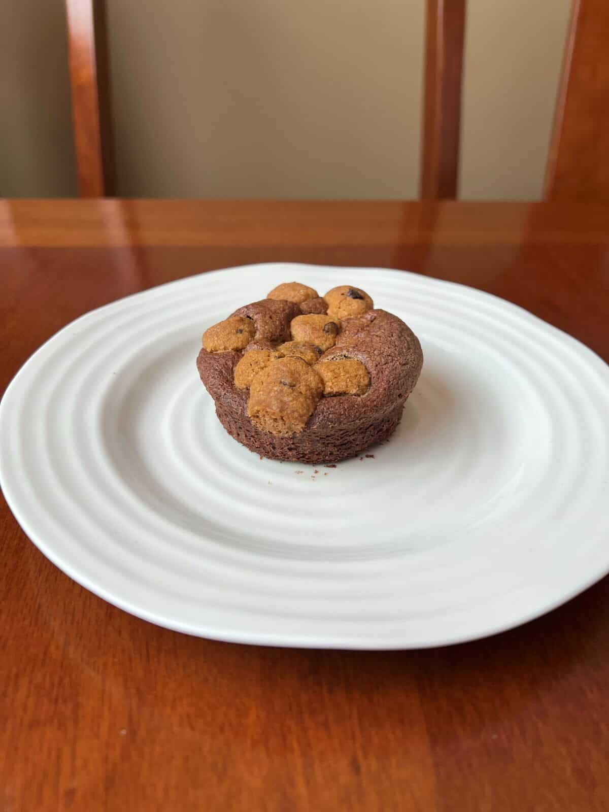 Image of one Brookie served on a white plate. There are chunks of cookie dough in the brownie. 