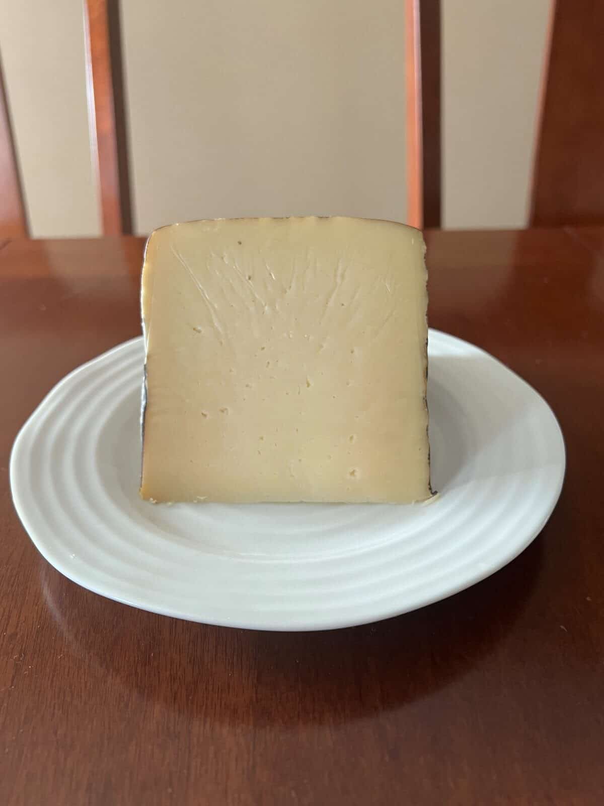 Image of a block of manchego sitting on a white plate. 