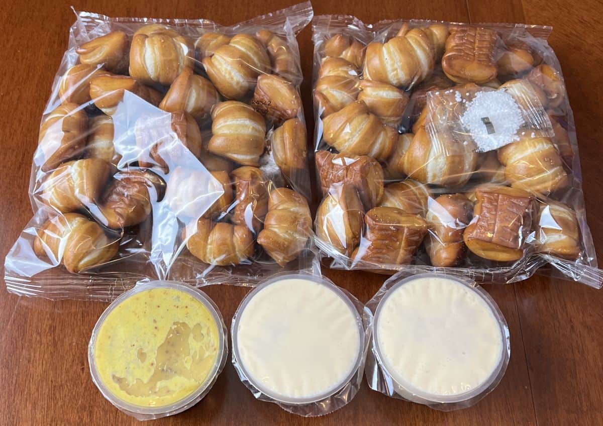 Image of two sealed bags of pretzel bites and three sealed dips sitting on a table. 