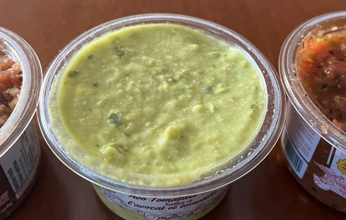 Top down image of an open container of avo tomatillo salsa.